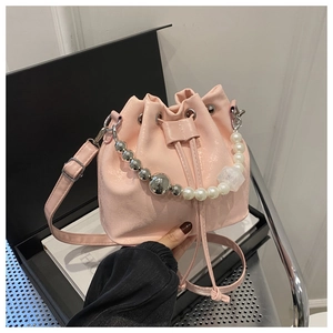 Détail du sac seau rose à cordon avec chaîne en perles et texture en PU brillant