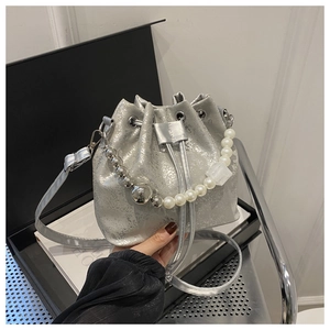 Détail du sac seau argenté avec anse en perles et texture métallique à cordon