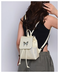 Detail of a champagne gold mini backpack with silver butterfly buckle on a model