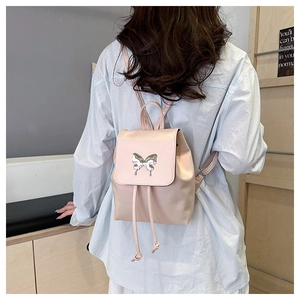 Pink leather mini backpack with silver butterfly charm on flip cover shown on model
