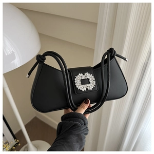 Détail du sac baguette noir avec boucle en strass argentés et poignée en corde