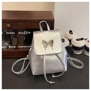 Detail of silver metallic backpack featuring a metal butterfly clasp and drawstring