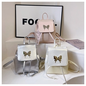 Detailed shot of three mini backpacks in pink, silver, and white with metal butterfly clips