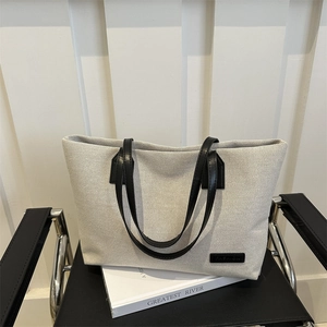 Minimalist off-white canvas tote bag with black leather handles for women commuting