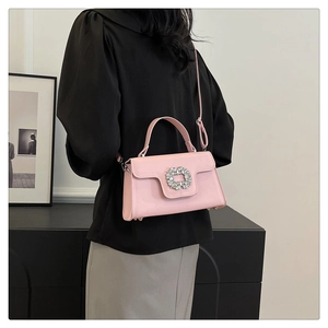 Detalle de bolso bandolera rosa claro con hebilla de strass plateada en un modelo