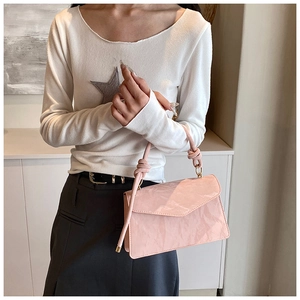 Close-up of pink wrinkled leather texture on a crossbody bag with dual knotted handles