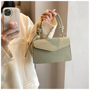 Pale green envelope flap handbag with metallic ring detail worn by a model in a suit