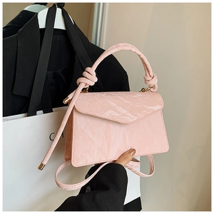 Detail of light pink patent leather crossbody bag with pleated texture and knot handle