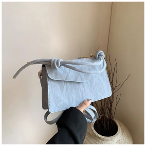 Macro detail of light blue crossbody bag with pleated texture and knotted handle