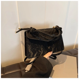 Detail of vintage black textured handbag with unique knotted handle and gold metal hardware