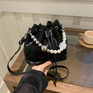 Sac seau noir tendance avec cordon de serrage, chaîne perlée et texture cuir verni