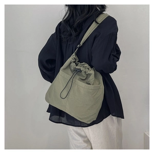 Olive green drawstring tote bag detail showing large capacity and front utility pockets