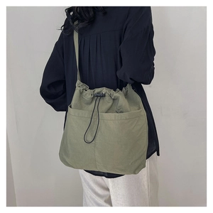 Detail of green nylon shoulder bag with adjustable strap and drawstring closure
