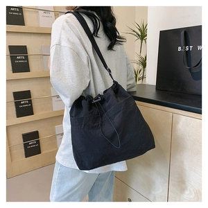 Detail of black drawstring bucket bag with functional side pocket and wide strap