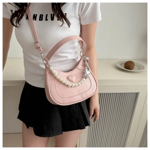 Detail of pink heart-embossed handbag with pearl chain and silver heart charm pendant