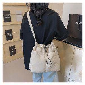 Detail view of large beige drawstring tote bag shown on model for size and capacity