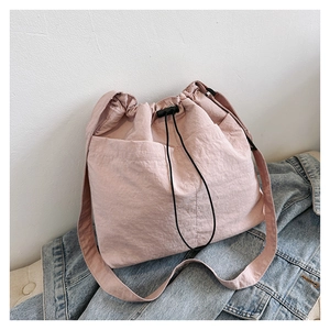 Detail view of pink drawstring bucket bag with natural wrinkled nylon texture and strap