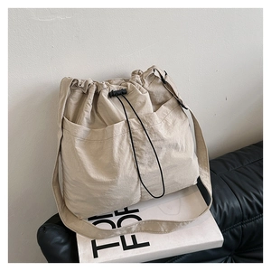 Detail of light beige nylon crossbody bag with dual drawstring pockets and textured fabric