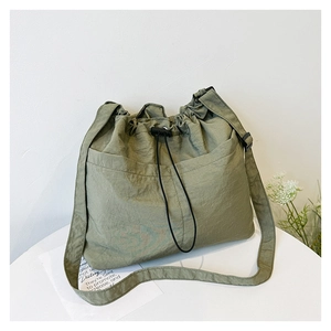 Detail of green nylon tote bag featuring drawstring closure and adjustable strap