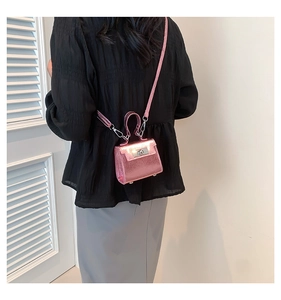 Mini pink metallic crossbody bag featuring silver turn-lock clasp worn by model