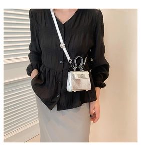 Detail of silver metallic mini square bag with a rotating metal lock and handle