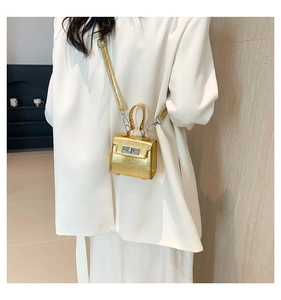 Detail of a golden mini laser kelly bag with mirror finish and silver hardware on a model