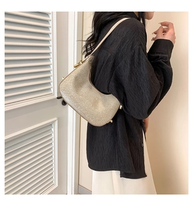 Close-up of crescent hobo bag with shimmering metallic glitter finish and golden buckle