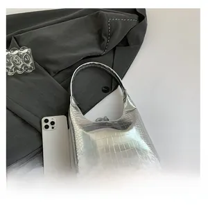 Vue détaillée de la texture crocodile argentée sur un petit sac à bandoulière avec zip