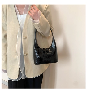 Détail du sac hobo noir à texture crocodile avec double fermeture éclair sur modèle