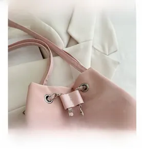 Detailed view of pink drawstring bucket bag with silver chain and textured leather finish