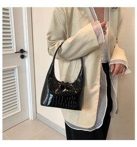Détail du sac hobo noir brillant à texture crocodile montrant la finition raffinée