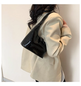 Sac hobo noir brillant à motif crocodile porté avec un blazer beige élégant