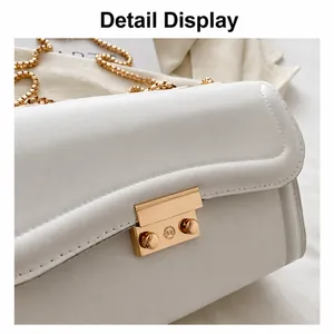 Close-up of white leather shoulder bag featuring a gold rectangular metal push-lock