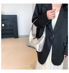 Détail de la texture motif crocodile argenté sur un sac à main métallique minimaliste