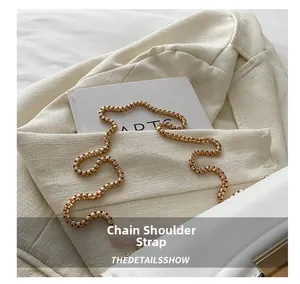 Detail of elegant gold chain strap on white quilted crossbody bag with luxury texture
