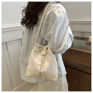 Detail der cremefarbenen Beuteltasche mit Silberkette und Kordelzug am Modell