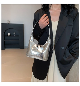 Sac hobo argenté brillant motif crocodile porté par un mannequin en costume noir
