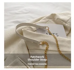 Detail of white leather shoulder strap with gold chain links and metallic D-ring