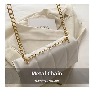 Detail of white quilted handbag with premium gold metal chain strap on a beige blazer