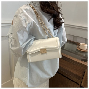 Détail du sac à bandoulière blanc minimaliste avec chaîne dorée et rabat ondulé