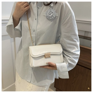 Gros plan d'un sac à chaîne en cuir verni blanc avec fermoir doré et détails floraux