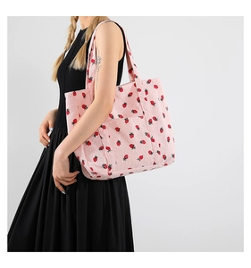 Dettaglio della borsa tote in velluto rosa con stampa fragole e tasca frontale
