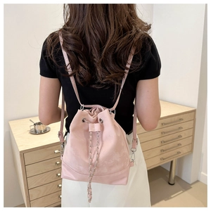 Detail view of pink bucket bag with silver chain drawstring on a casual model outfit