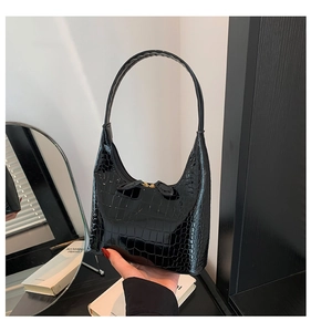 Détail du sac à bandoulière en similicuir croco brillant noir avec fermeture dorée