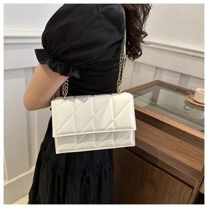 Close-up of white quilted crossbody bag with gold chain strap worn by a model