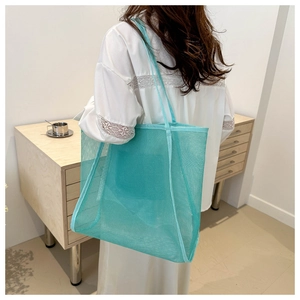 Vista dettagliata della borsa tote in rete verde lime portata a spalla da una donna