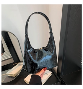 Gros plan sur le sac hobo en cuir verni noir motif crocodile avec détails dorés