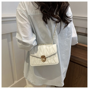 Détail du sac bandoulière matelassé blanc avec fermoir tournant doré et bandoulière chaîne