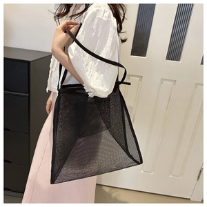 Detail of transparent black mesh tote bag with thin double straps worn by model for scale