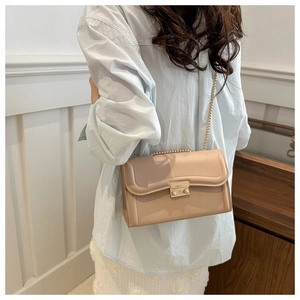 Détail du sac beige avec chaîne dorée, fermoir métallique et surpiqûres ondulées chic